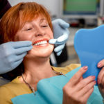 Red haired woman checking out her smile at the dentist