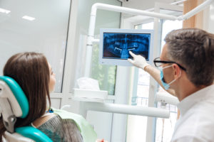 Dentist pointing out signs of a cavity on an xray