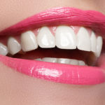 Closeup of woman's smiling lips with pink lipstick