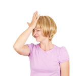 Blonde woman in pink shirt smacking her forehead.