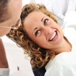 Woman with blonde curly hair smiling while she talks to the dentist