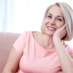 Older woman in pink shirt sitting on a couch
