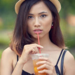 Asian woman with an orange drink at the park