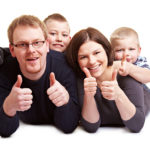 Happy family of four giving a thumbs up.